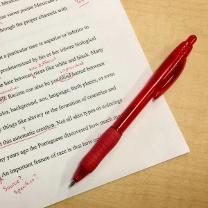 Ein roter Stift liegt auf einem beschriebenen Blatt Papier für das Korrektorat.