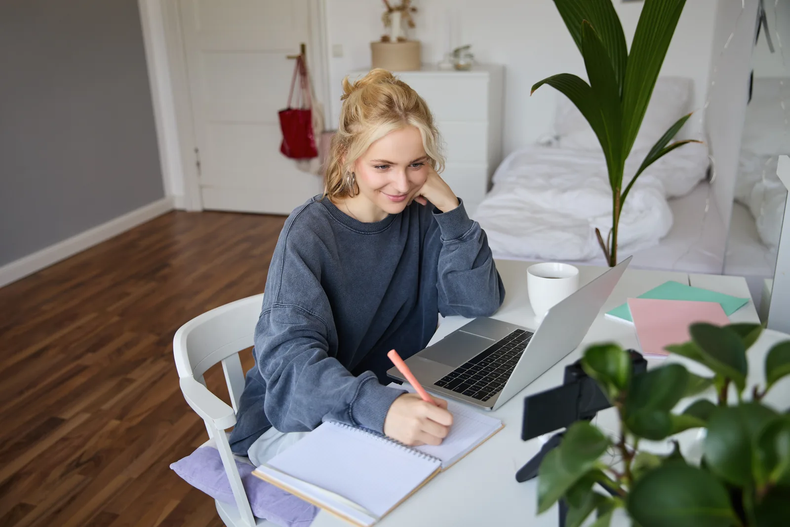 autorin-schreibt-zuhause Autorin schreibt zu Hause am Schreibtisch an ihrem Manuskript, daneben ein Laptop